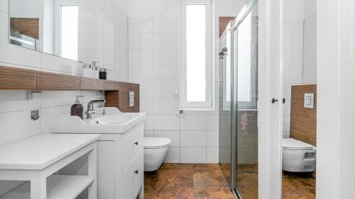 uma casa de banho branca com um lavatório e um WC em VENTI Sopot Broniewskiego 1 em Sopot