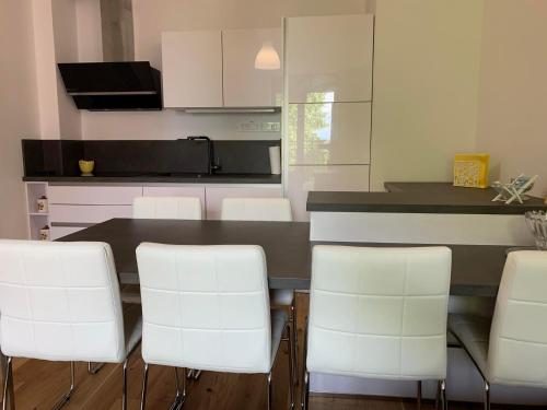 een keuken met een tafel en een aantal witte stoelen bij APARTMA KOPER ZVER in Koper