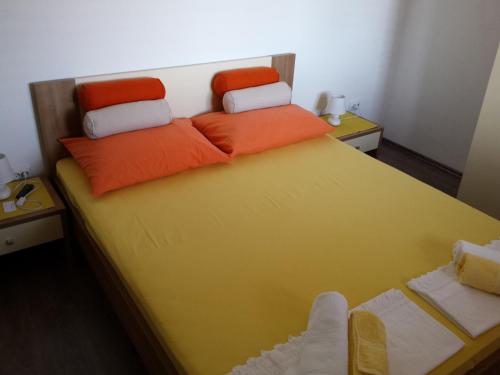 a bed with two orange pillows on top of it at Guest House Sombrero in Senj