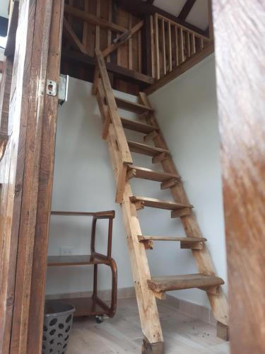 a wooden spiral staircase in a room with a chair at Finca Maracuba Cabañas Limón, Manzana y Níspero in Jardin