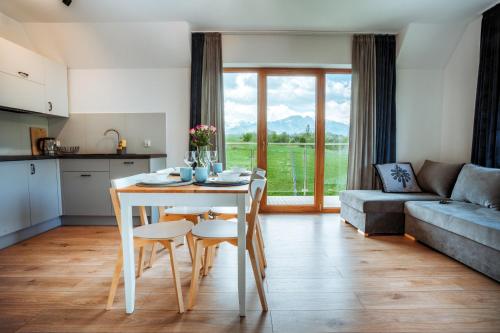 a kitchen and living room with a table and chairs at Apartamenty Widok Tatr in Zakopane