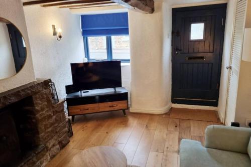 a living room with a television and a fireplace at 1750's cottage with open fire and beams in Upholland