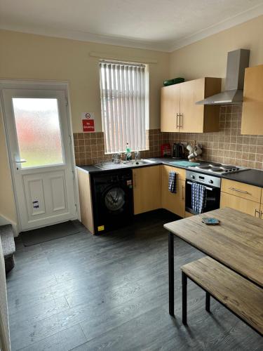 a kitchen with a stove and a sink and a table at Cosy house in Wombwell in Barnsley