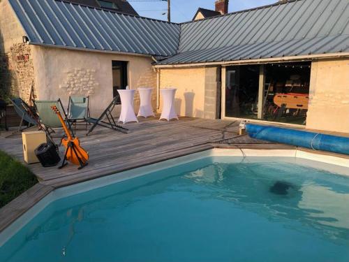 uma piscina com cadeiras e um deque de madeira em Maison de ville atypique em Le Molay-Littry