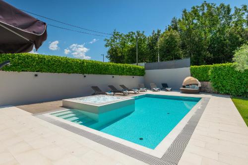 a swimming pool in a yard with chairs around it at Villa Mala in Umag