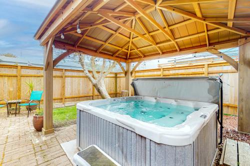a hot tub in a backyard with a wooden roof at Ocean Shells Cottage in Rockaway Beach