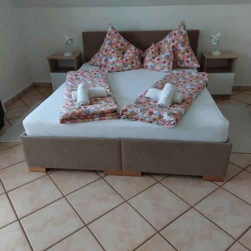 a bed with pillows on it in a room at Erika Apartmanházak in Hévíz