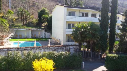 un grand bâtiment blanc avec une piscine et des arbres dans l'établissement Hotel Maximilian, à Merano