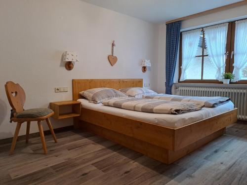 a bedroom with a large wooden bed and a chair at Landhaus Thaumiller in Oberstdorf