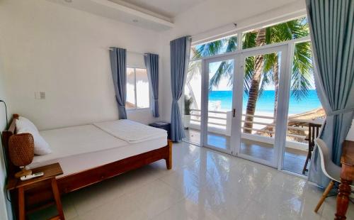 a bedroom with a bed and a view of the ocean at Lucky Spot Beach Bungalow in Song Cau