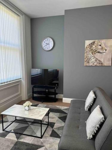 uma sala de estar com um sofá e um relógio na parede em NEW HMM Apartmentz - Free parking - Beautiful area em Sunderland