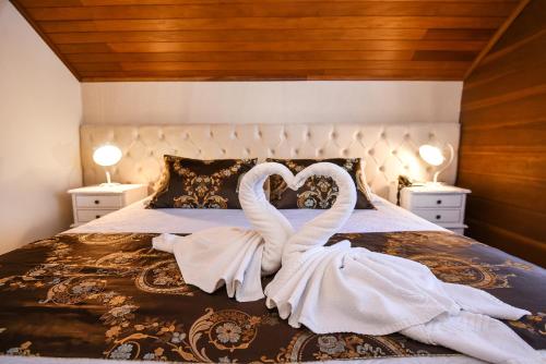 two swans dressed in white are sitting on a bed at Hotel Kehl Haus in Gramado