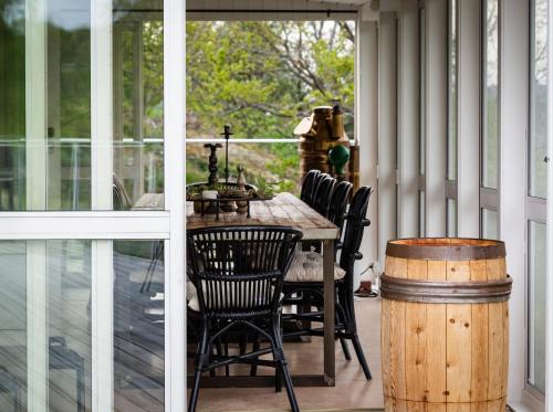 porche cubierto con mesa, sillas y barril en Exclusive house with private boathouse, en Nösund