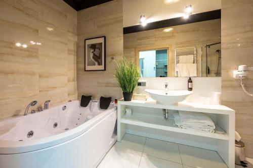 a bathroom with a large tub and a sink at Hotel Atelia in Lublin