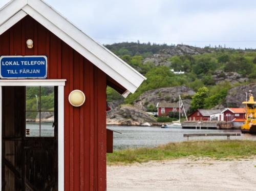 a red building with a sign on it next to a body of water at Exclusive house with private boathouse in Nösund