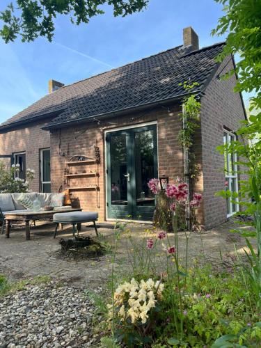 a brick house with a bench in front of it at Huisje Hygge - luxe bungalow met grote tuin in Ewijk