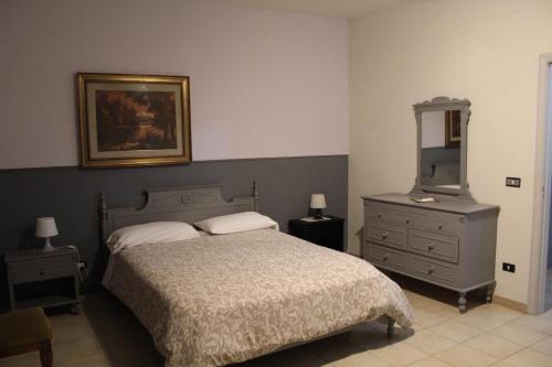 una camera con letto, cassettiera e specchio di Il Giardino degli Agrumi a Caserta