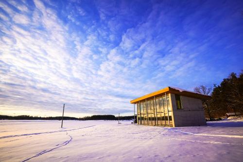 a small building sitting in a snow covered field at Pakalni in Aizkraukle