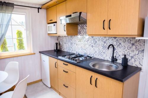 uma cozinha com um lavatório, um fogão e uma janela em Domki wakacyjne Koral em Swarzewo