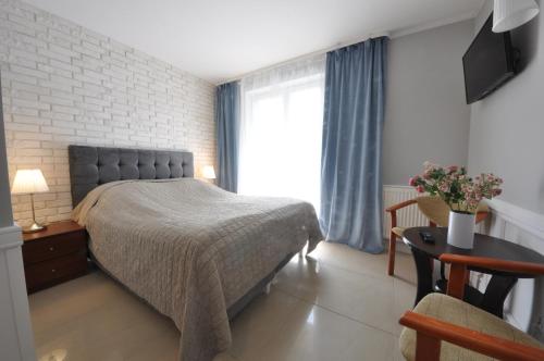 a bedroom with a bed and a table and a window at Ambasador Villa, 150m do plaży, przy Centrum in Mielno