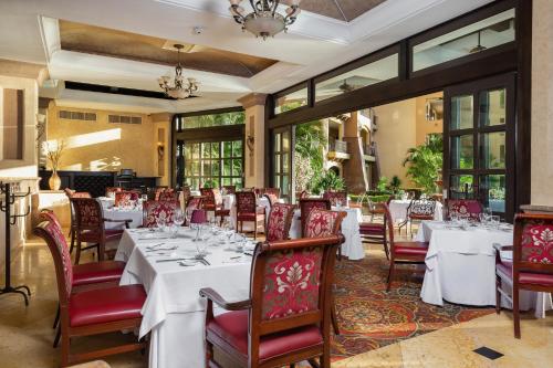 a dining room with white tables and red chairs at Villa La Estancia Beach Resort & Spa Riviera Nayarit in Nuevo Vallarta