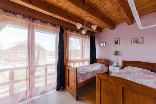 a bedroom with two beds and a large window at Apartman egy Makovecz Imre tervezte házban in Ispánk