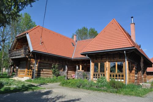 a large wooden house with a red roof at Apartman egy Makovecz Imre tervezte házban in Ispánk