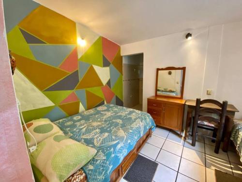een slaapkamer met een bed en een kleurrijke muur bij La Casita, en centro de la ciudad de Oaxaca in Oaxaca City