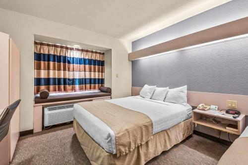una camera d'albergo con un grande letto e una finestra di Microtel Inn & Suites by Wyndham Sainte Genevieve a Sainte Genevieve