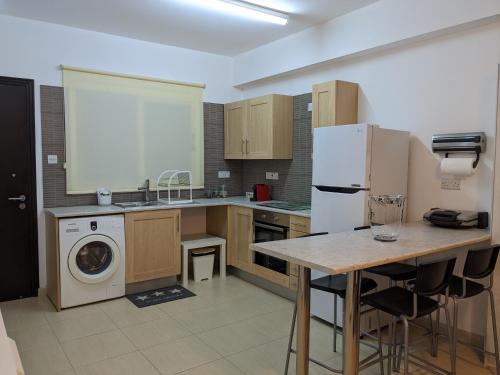 een keuken met een koelkast, een wasmachine en een droger bij Cozy ground floor appartment with communal pool in Paralimni