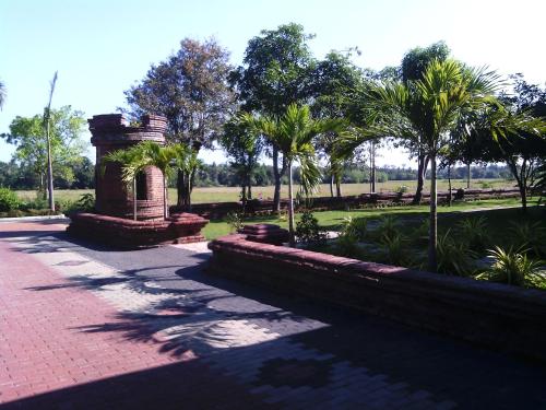 a park with palm trees and a brick walkway at Ruins Chaaya Hotel in Polonnaruwa