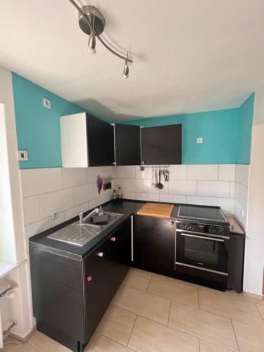 a kitchen with black cabinets and a stove at Ruhige Ferienwohnung im Saarland in Schiffweiler