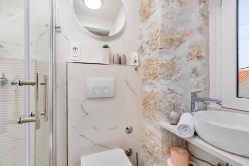 a white bathroom with a sink and a mirror at Guest house Otto in Punat