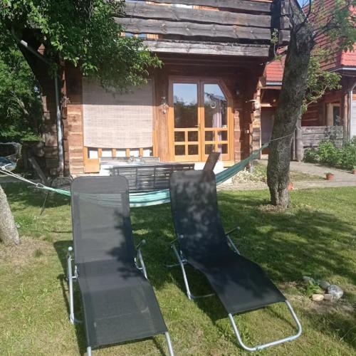 two chairs sitting in the grass in front of a house at Apartman egy Makovecz Imre tervezte házban in Ispánk