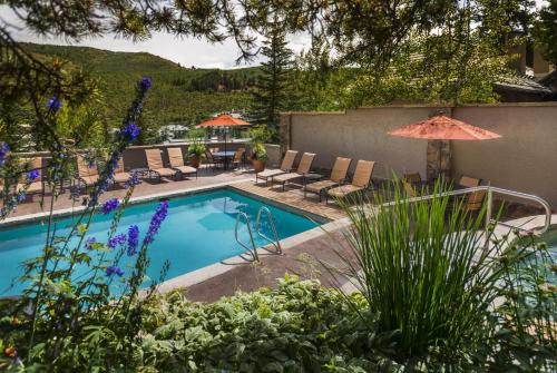 a pool with chairs and umbrellas in a yard at The Pines Lodge, a RockResort, by Vail Resorts in Beaver Creek