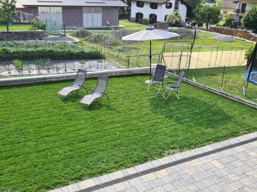 a group of chairs and an umbrella on a lawn at Casa Vacanza Lo Nânò in Fenis