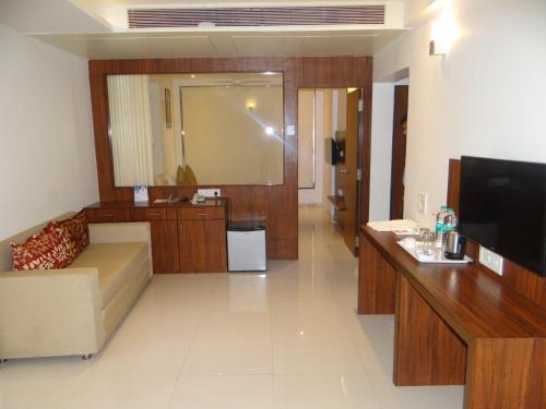 a living room with a couch and a flat screen tv at The Temple View Hotel in Shirdi