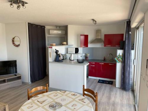 a kitchen with red cabinets and a white counter top at le Barcarès appartement bord de mer in Le Barcarès