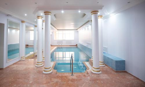a large indoor pool with columns and a swimming pool at Amsterdam Hotel Aktobe in Aktobe