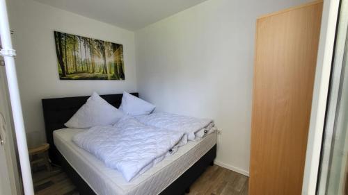 - un lit avec des draps et des oreillers blancs dans l'établissement Ferienwohnung Auenglück Hahnenklee Harz, à Hahnenklee