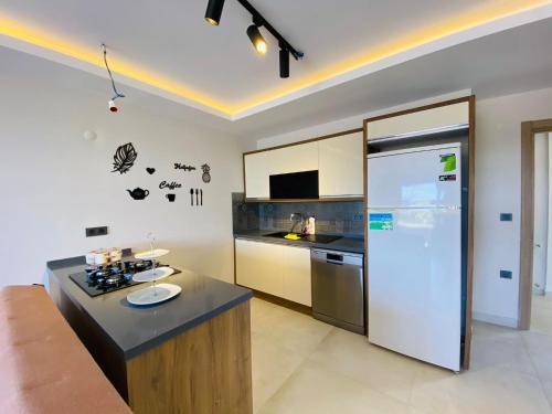 een keuken met een aanrecht en een koelkast bij KUSADASI SOGUCAKTA 2+1 TERASLI DENIZE YAKIN LUKS DAIRE in Kuşadası