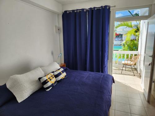 a bedroom with a bed with blue curtains and a balcony at OEManagement Hotel Rooms in Roseau