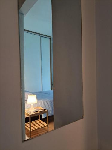 a mirror reflecting a bedroom with a bed and a table at Νέο στούντιο, Νέος Κόσμος in Athens