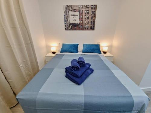 duże niebieskie łóżko z dwoma niebieskimi ręcznikami w obiekcie Apartamentos Bielsa 'Madrid Río' w Madrycie