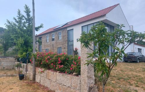 a house with a stone wall and flowers in a yard at Turismo Rural Macieira Brava in Guarda