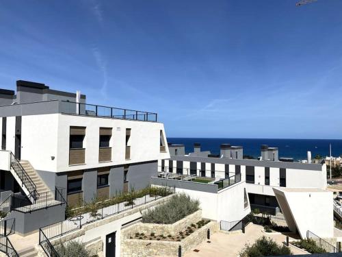 um edifício branco com o oceano ao fundo em Gran Apartment-Iconic Sea View em Gran Alacant