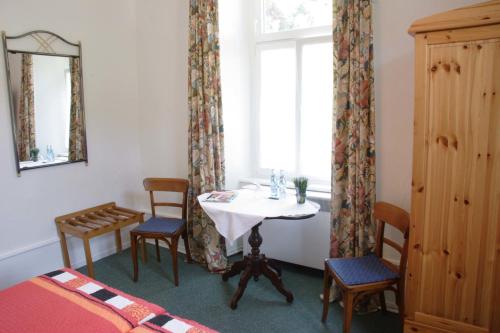 une chambre avec une table, des chaises et une fenêtre dans l'établissement Pension Waldheim, à Fribourg-en-Brisgau