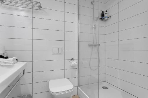 a white bathroom with a toilet and a shower at Icelandic Apartments by Heimaleiga in Reykjavík