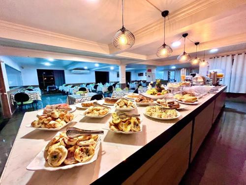 a buffet line with many plates of food on it at Hotel Fenice in Foz do Iguaçu