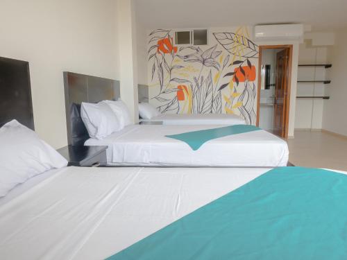 a bedroom with two beds and a painting on the wall at Margaritas Palace Hotel in Canoa